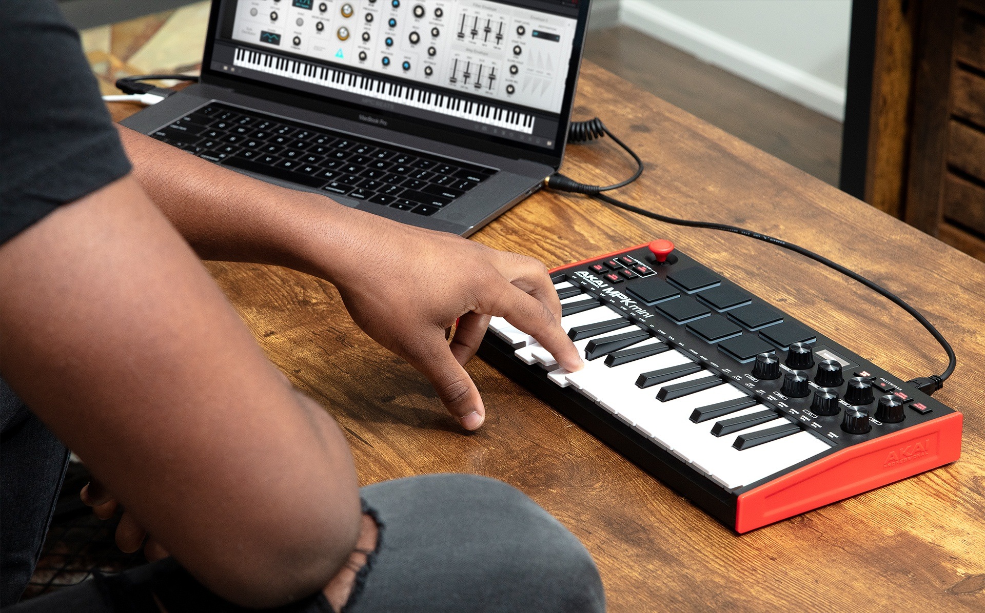 Music producer playing MPK Mini keys on laptop with MPC Beats